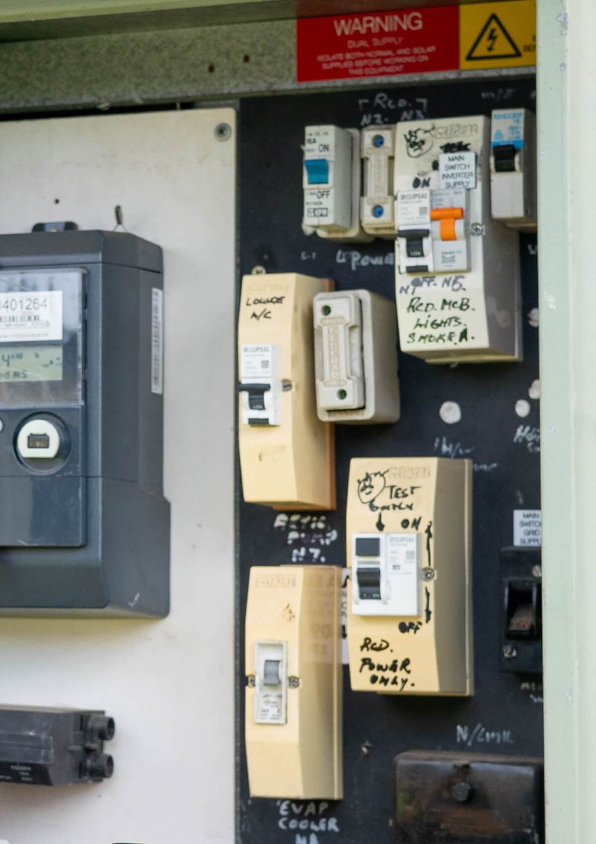 Close-up of a residential switchboard showing multiple labelled circuit breakers, RCDs, and a digital electricity meter installed on an external wall