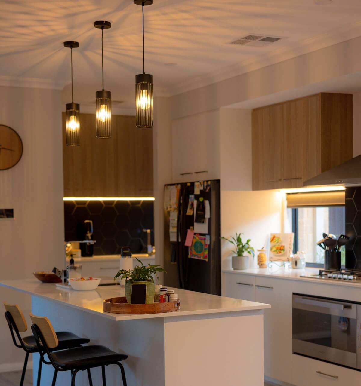 Interior view of a modern kitchen with feature pendant lights and ambient LED strip lighting, ideal for showcasing residential lighting installations