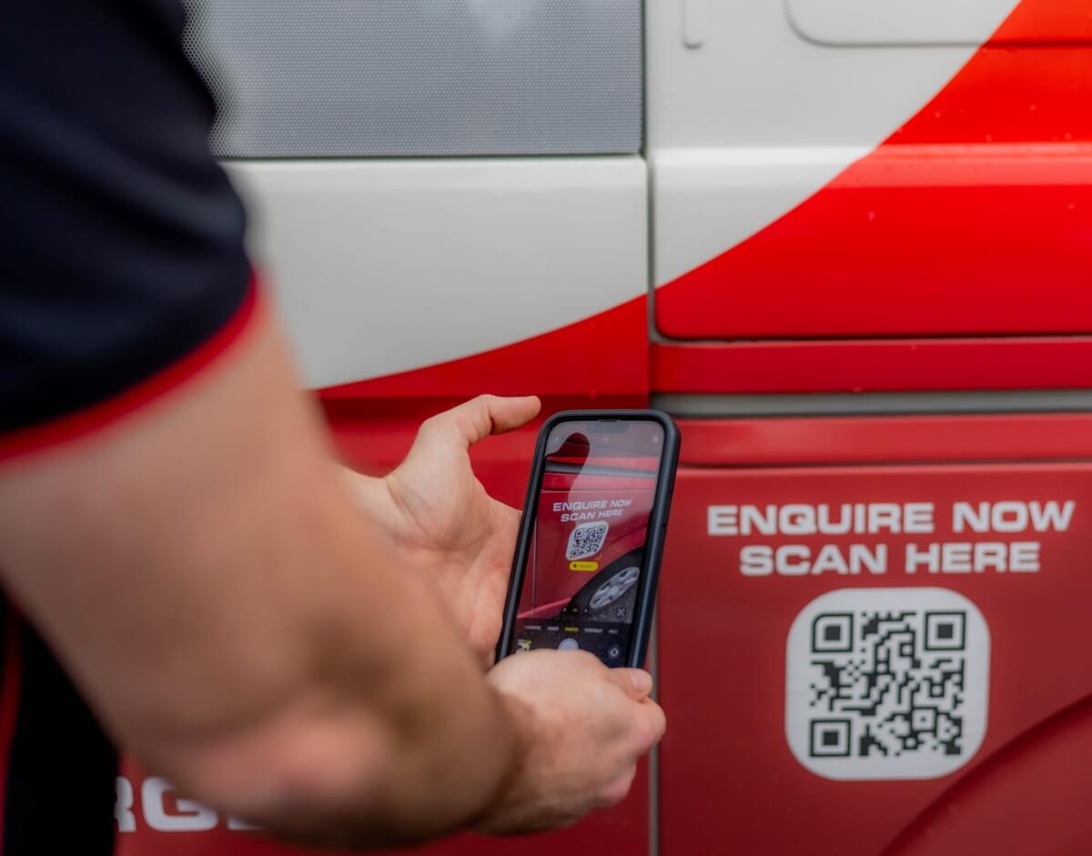A potential customer scanning a QR code on a PWA Electrical Services van for quick access to online enquiries or service bookings