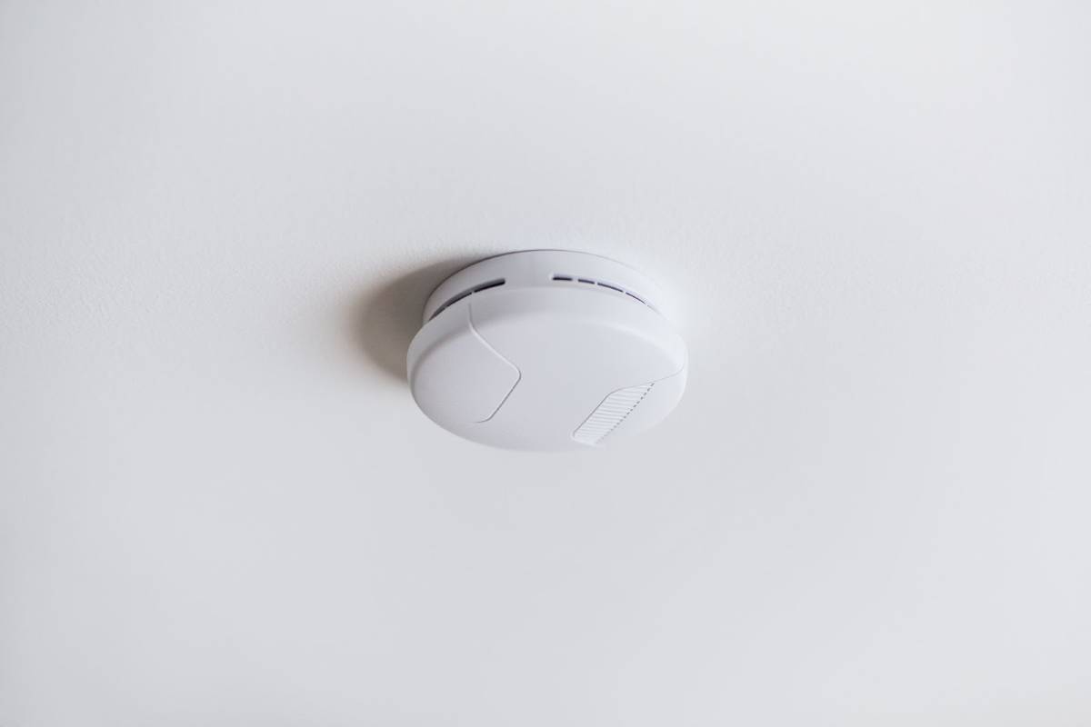 Ceiling-mounted smoke alarm close-up, installed in a modern residential interior.