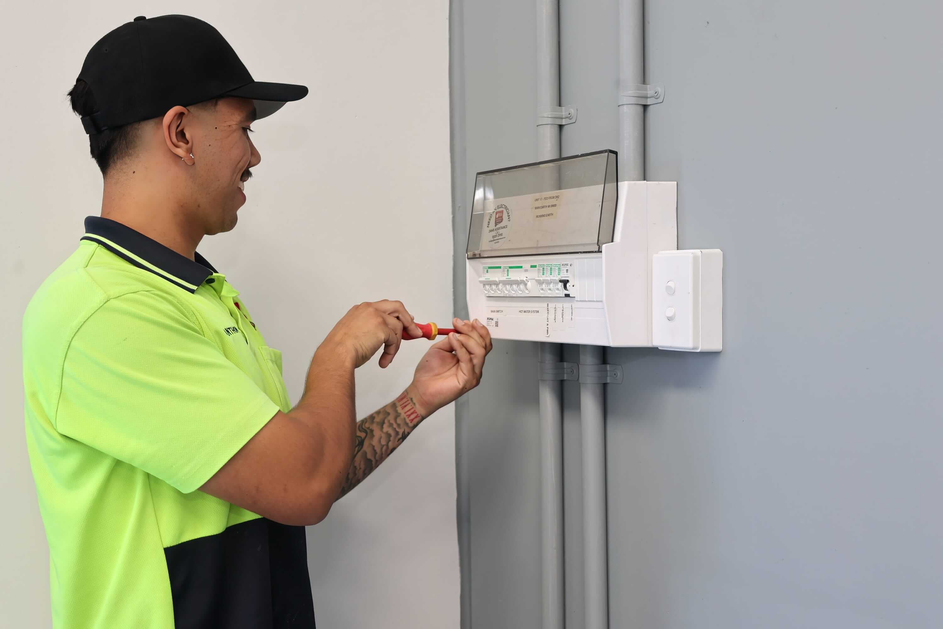Licensed electrician working on a residential switchboard installing or adjusting electrical components.