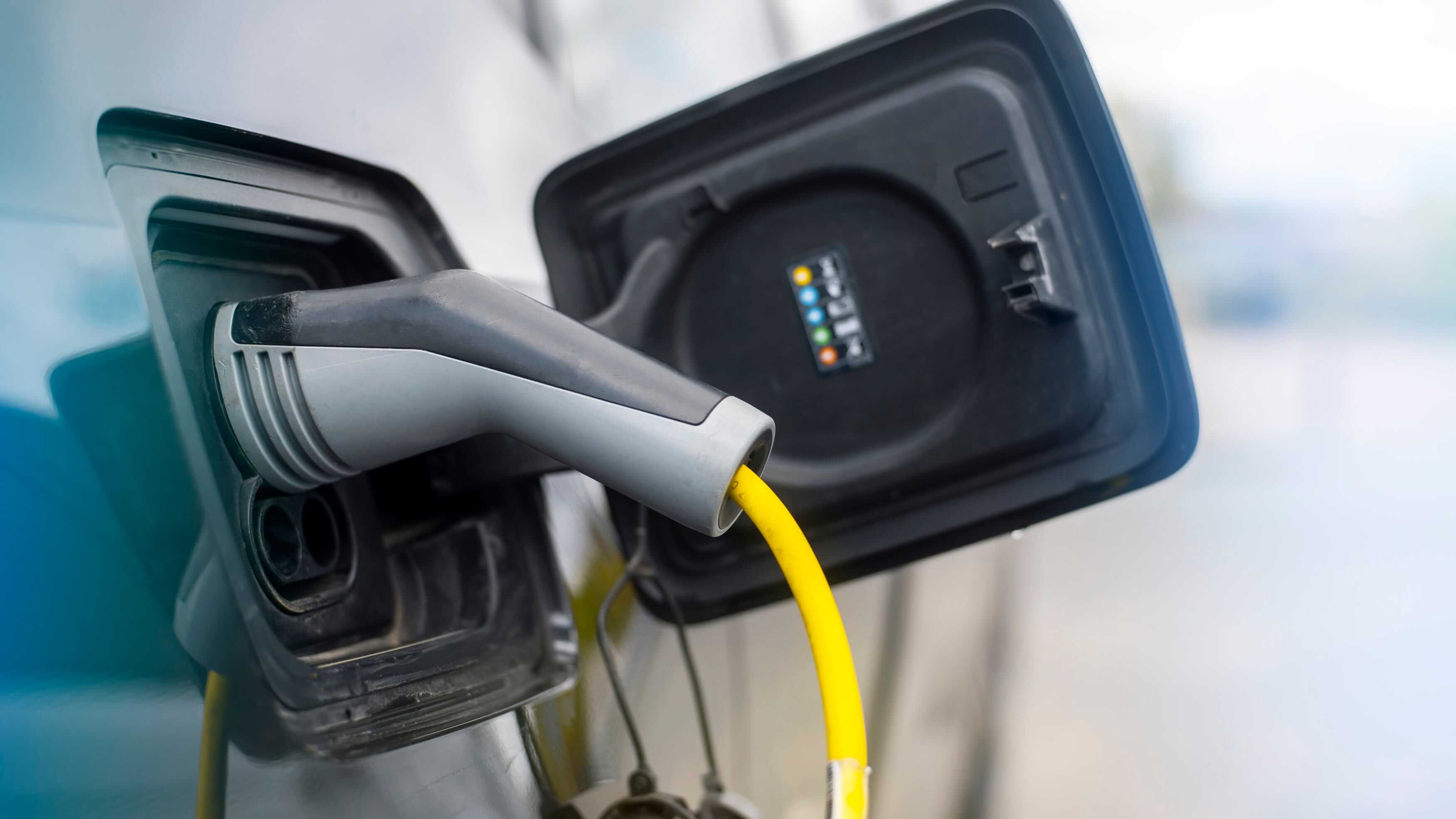 Electric vehicle charging cable connected to a car at a residential charging station.