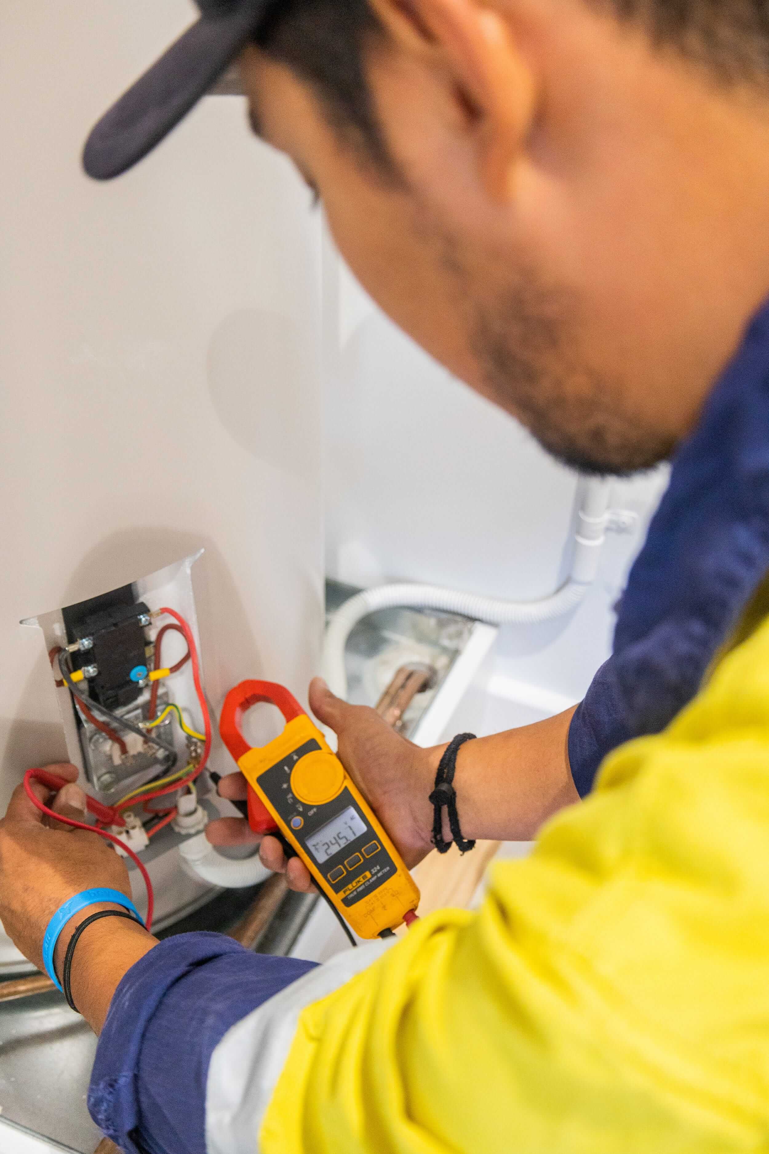 PWA Electrical Services electrician using a clamp meter to test electrical wiring during a residential installation.