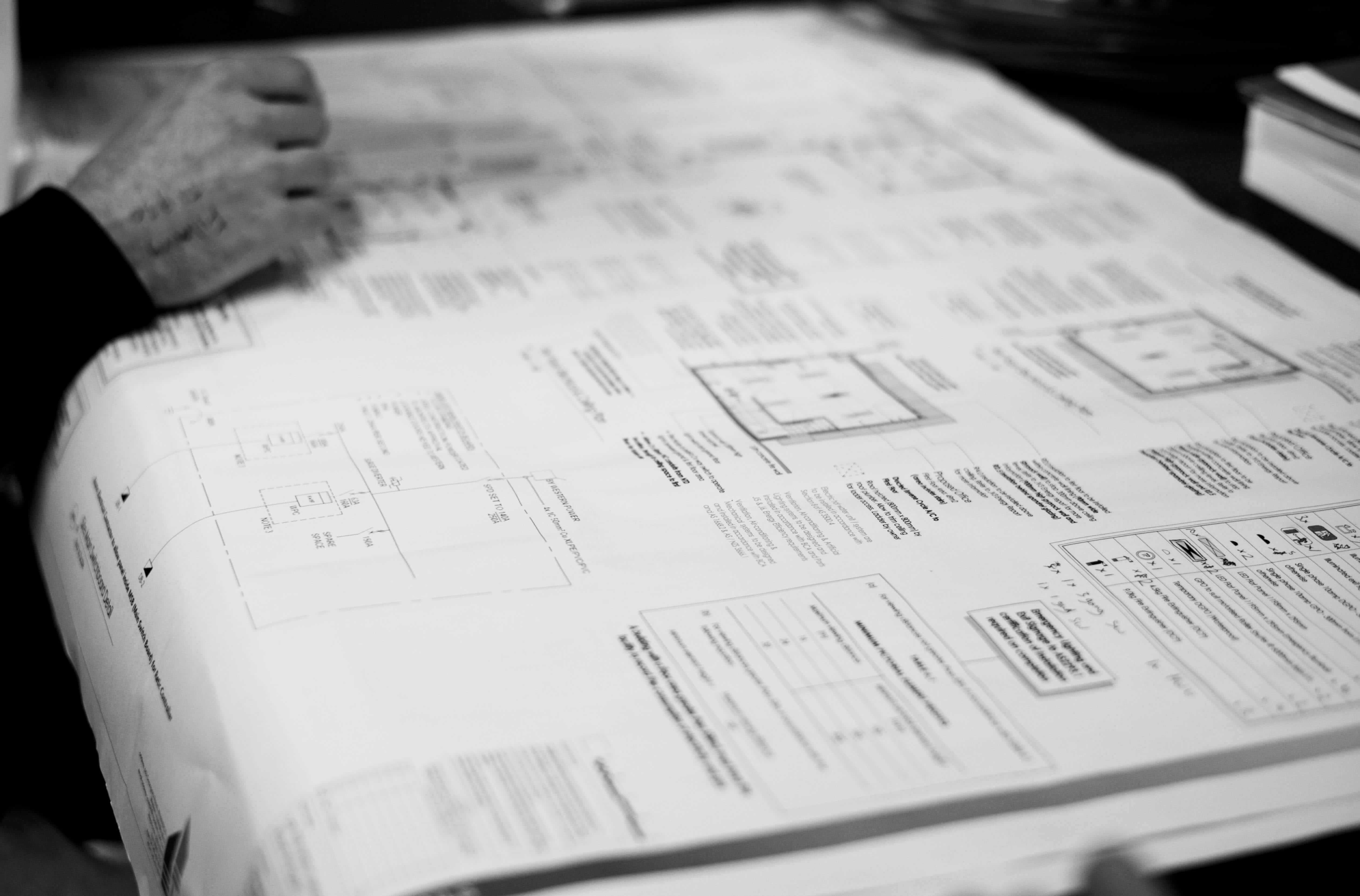 Electrical engineer reviewing large-format wiring diagrams and technical plans on a desk.