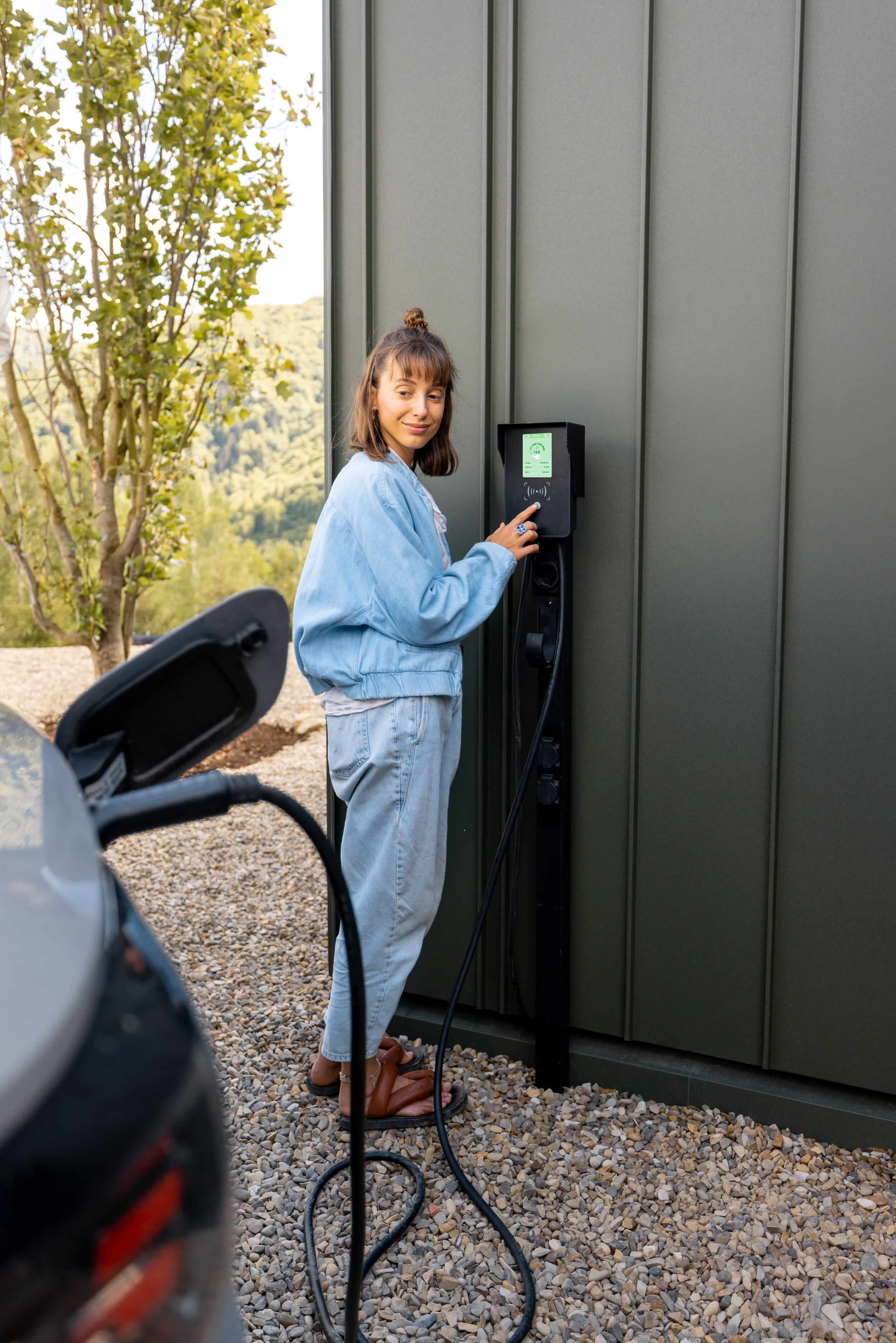 Homeowner charging an electric vehicle using a wall-mounted EV charging station.